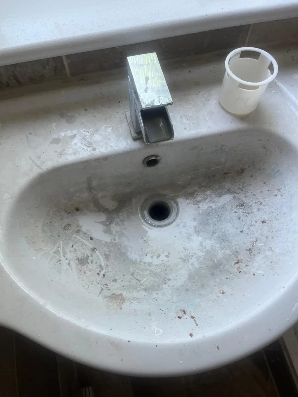 Round basin stained with limescale and dirt before move-in clean
