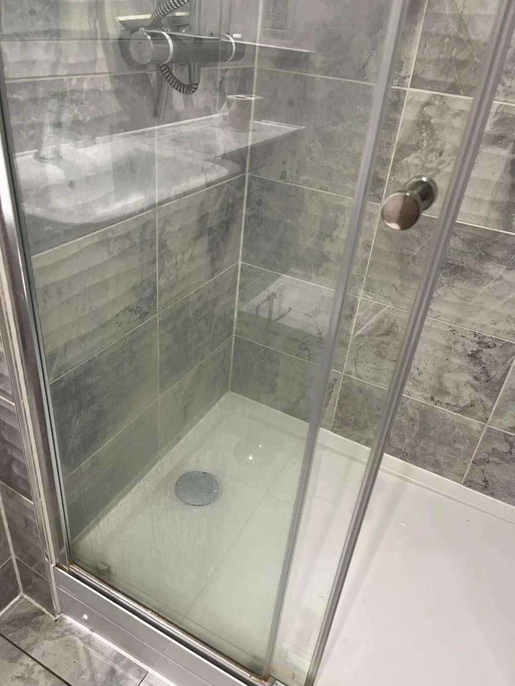 Glass shower enclosure clouded with limescale before descaling